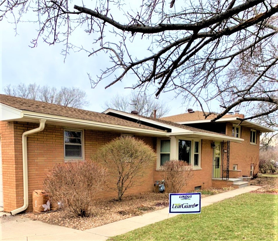 Photo of a mid-sized midcentury one-storey brick orange house exterior in Minneapolis with a shingle roof and a brown roof.