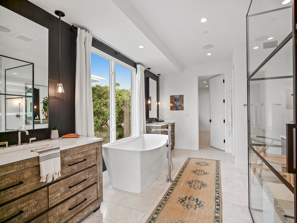 Design ideas for a large beach style master bathroom in Orange County with light wood cabinets, a freestanding tub, an alcove shower, black tile, ceramic tile, white walls, marble floors, an undermount sink, beige floor, a hinged shower door, white benchtops and flat-panel cabinets.