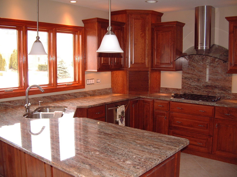 Photo of a mid-sized traditional u-shaped eat-in kitchen in Chicago with an undermount sink, raised-panel cabinets, dark wood cabinets, granite benchtops, stainless steel appliances and a peninsula.