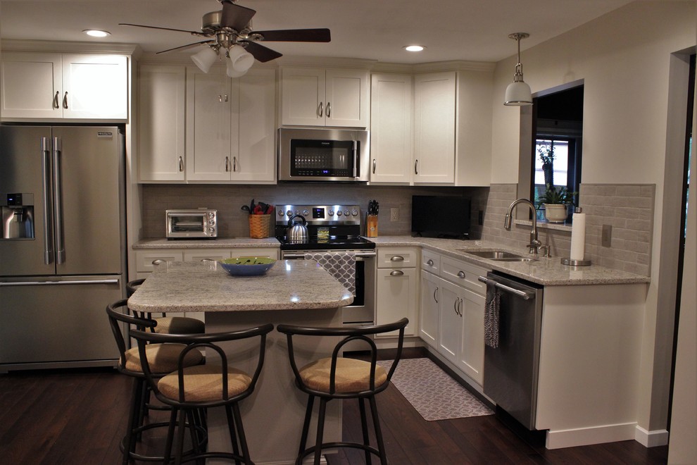 Photo of a mid-sized transitional l-shaped separate kitchen in Philadelphia with an undermount sink, shaker cabinets, white cabinets, quartz benchtops, grey splashback, porcelain splashback, stainless steel appliances, dark hardwood floors and with island.