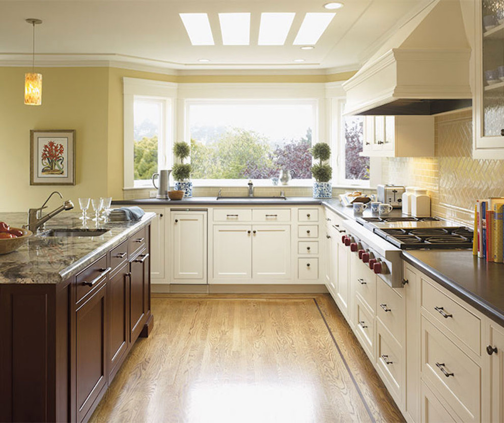 Eat-in kitchen - mid-sized transitional l-shaped medium tone wood floor and brown floor eat-in kitchen idea in Chicago with an undermount sink, recessed-panel cabinets, white cabinets, beige backsplash, glass tile backsplash, stainless steel appliances, an island and solid surface countertops