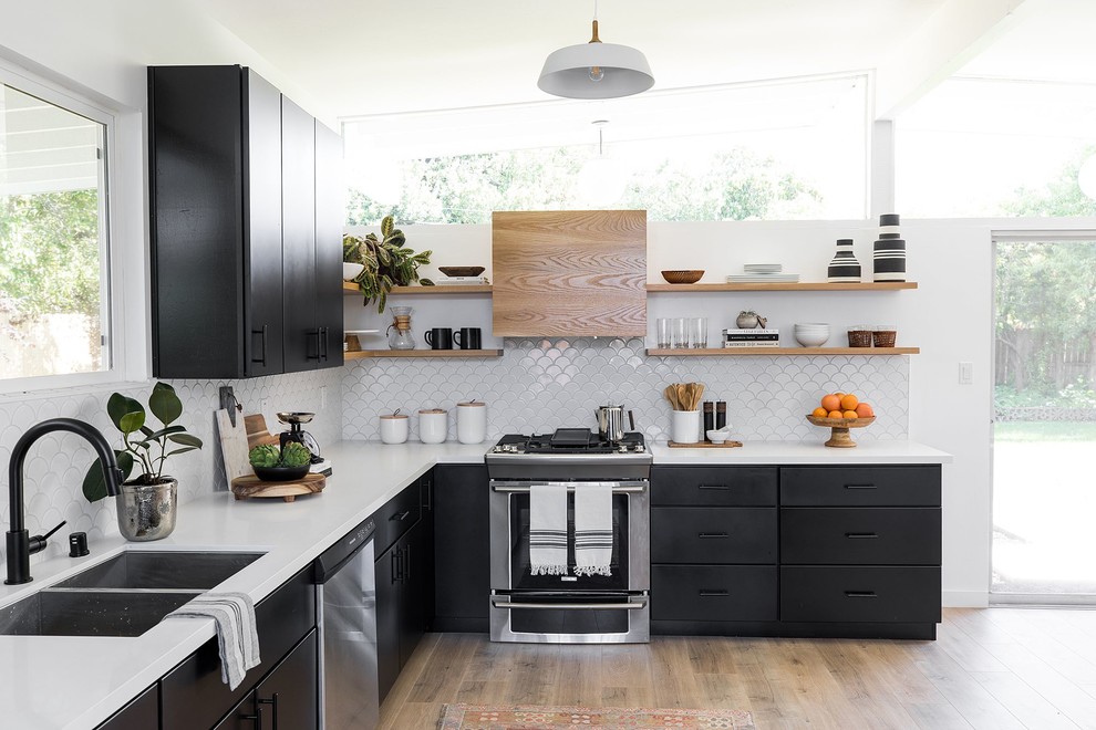 Inspiration for a midcentury l-shaped kitchen in Sacramento with a double-bowl sink, flat-panel cabinets, white splashback, stainless steel appliances, light hardwood floors, no island, beige floor and white benchtop.