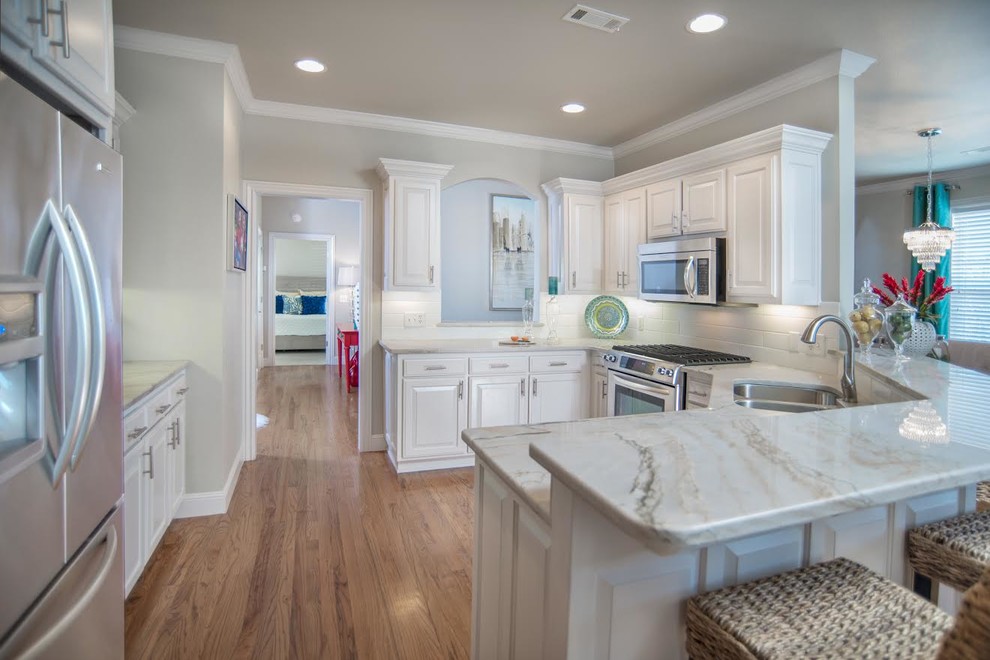Inspiration for a large transitional u-shaped light wood floor open concept kitchen remodel with a double-bowl sink, raised-panel cabinets, white cabinets, granite countertops, yellow backsplash, ceramic backsplash, stainless steel appliances and a peninsula