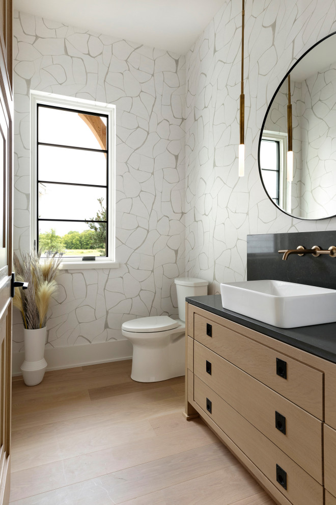 Transitional light wood floor and wallpaper powder room photo in Minneapolis with white cabinets, white walls, a vessel sink, quartz countertops, black countertops and a built-in vanity