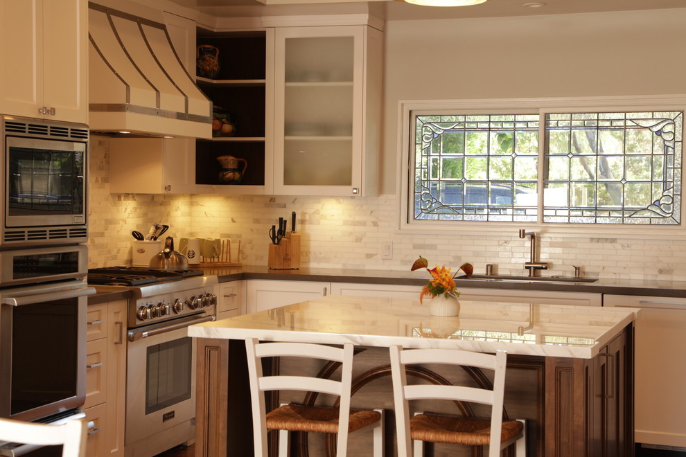 Large transitional u-shaped medium tone wood floor eat-in kitchen photo in Los Angeles with an undermount sink, recessed-panel cabinets, white cabinets, wood countertops, white backsplash, stone tile backsplash, stainless steel appliances and an island