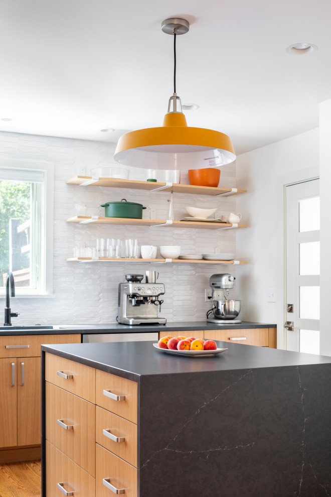 Inspiration for a mid-sized midcentury l-shaped separate kitchen in Seattle with an undermount sink, flat-panel cabinets, medium wood cabinets, soapstone benchtops, white splashback, ceramic splashback, stainless steel appliances, medium hardwood floors, with island and black benchtop.