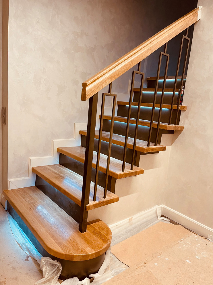 На фото: прямая лестница среднего размера в классическом стиле с деревянными ступенями, крашенными деревянными подступенками, металлическими перилами и обоями на стенах с