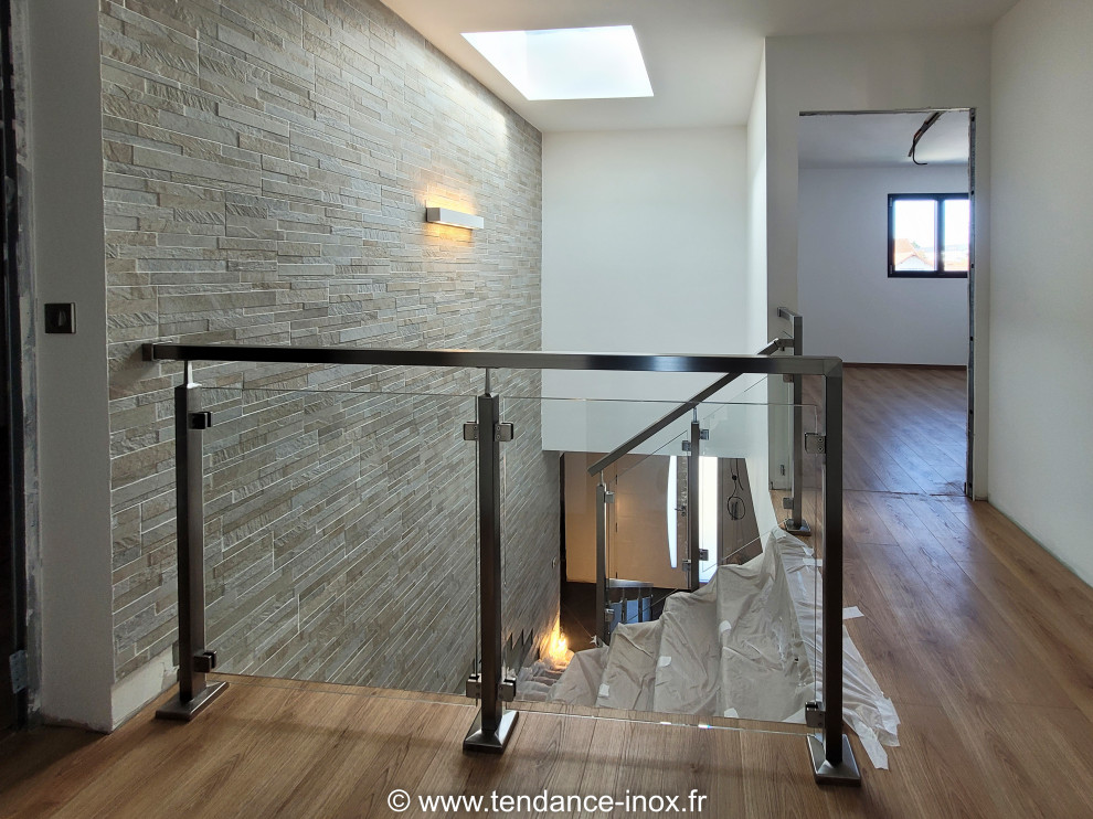 This is an example of a medium sized modern l-shaped glass railing staircase in Paris.