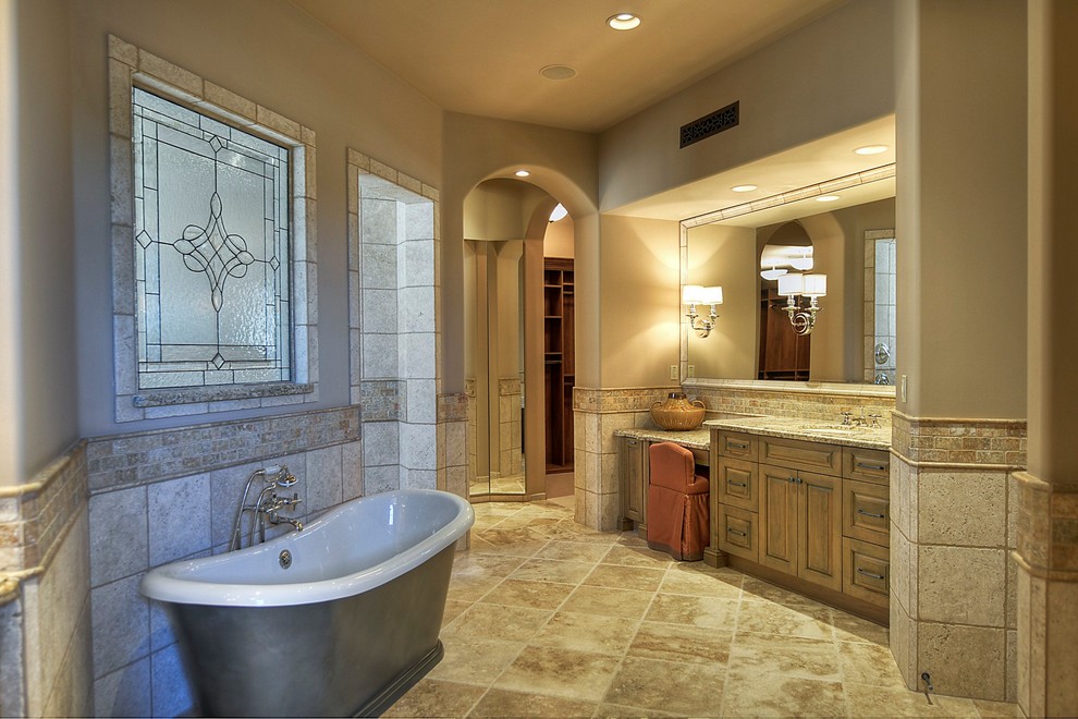 Inspiration for an expansive traditional bathroom in Phoenix with medium wood cabinets, granite benchtops, a freestanding tub, a double shower, a two-piece toilet, beige tile, stone tile and beige walls.