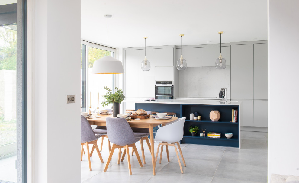 Inspiration for a contemporary galley eat-in kitchen in Dublin with flat-panel cabinets, grey cabinets, white splashback, stone slab splashback, stainless steel appliances, with island, grey floor and white benchtop.