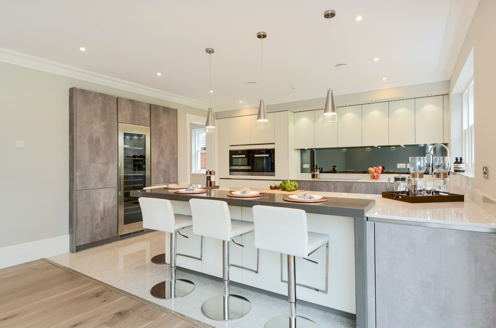 Inspiration for a mid-sized modern u-shaped eat-in kitchen in Berkshire with a drop-in sink, flat-panel cabinets, white cabinets, quartzite benchtops, grey splashback, mirror splashback, panelled appliances and a peninsula.