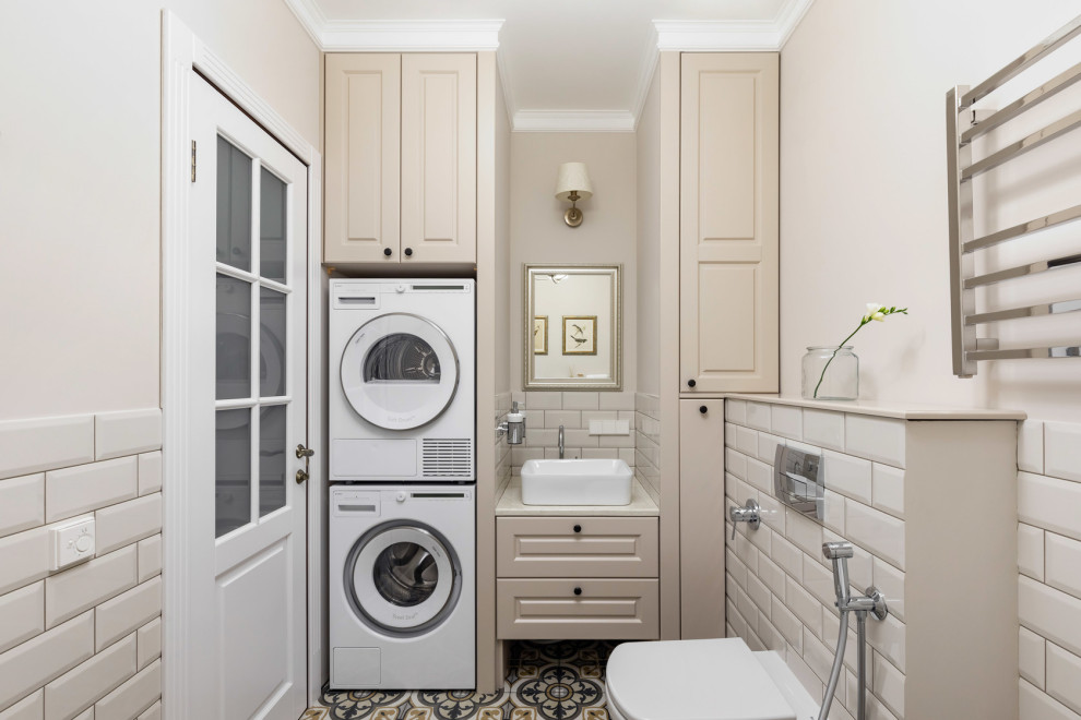 This is an example of a traditional 3/4 bathroom in Saint Petersburg with raised-panel cabinets, beige cabinets, a wall-mount toilet, beige tile, subway tile, beige walls, a vessel sink, multi-coloured floor and beige benchtops.