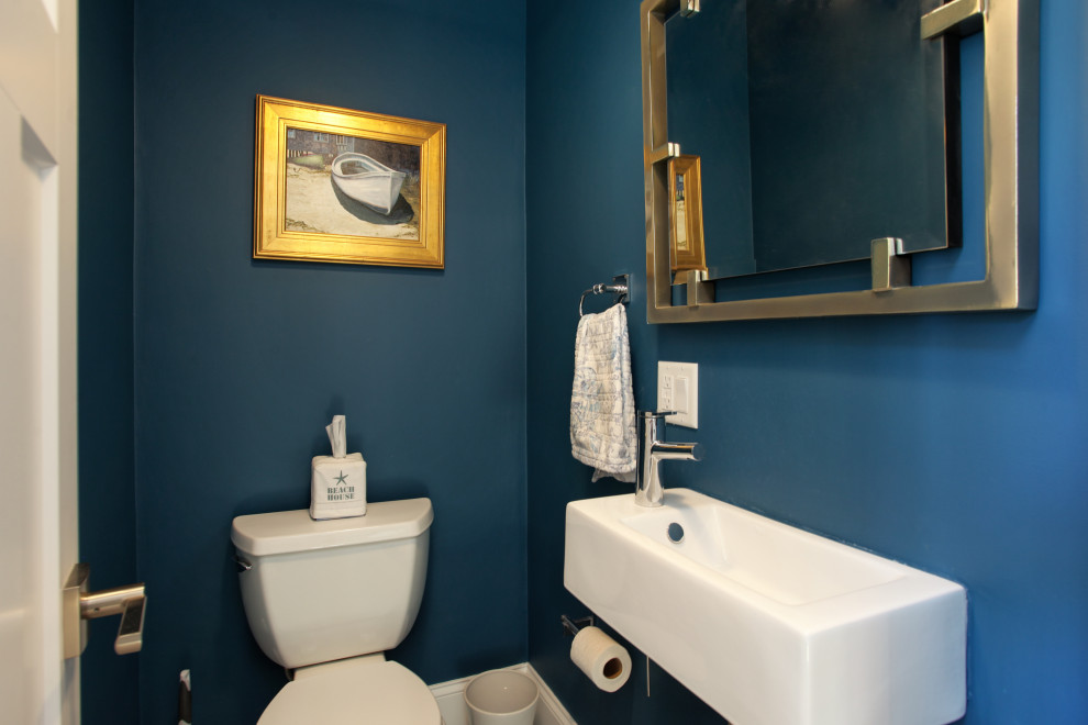 Powder room - small cottage powder room idea in Other with a one-piece toilet, blue walls, a wall-mount sink and a floating vanity