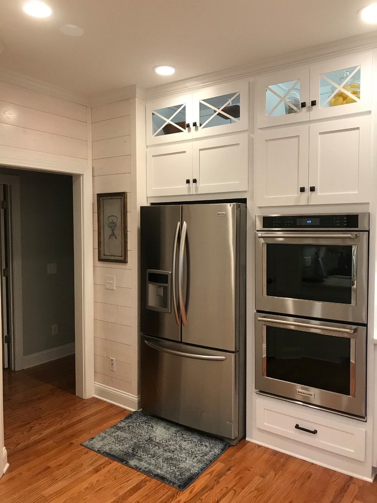 Inspiration for a mid-sized transitional u-shaped medium tone wood floor and brown floor eat-in kitchen remodel in Atlanta with a farmhouse sink, shaker cabinets, white cabinets, subway tile backsplash, stainless steel appliances, an island and granite countertops