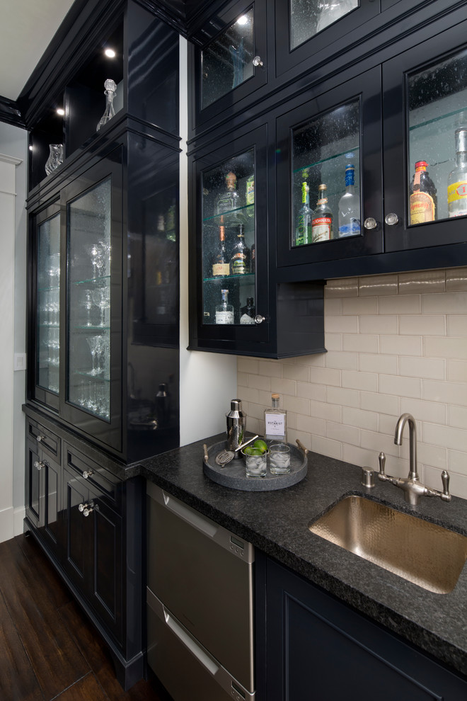 This is an example of a mid-sized traditional single-wall wet bar in San Francisco with an undermount sink, glass-front cabinets, black cabinets, granite benchtops, white splashback, subway tile splashback and dark hardwood floors.