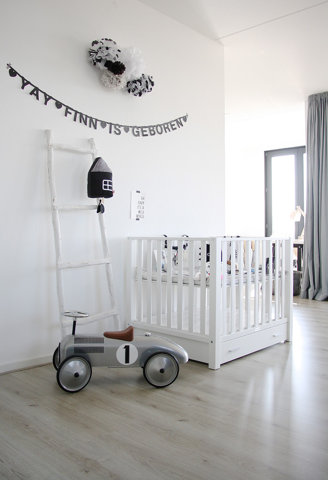Scandinavian nursery in Amsterdam with white walls, light hardwood floors and beige floor for boys.