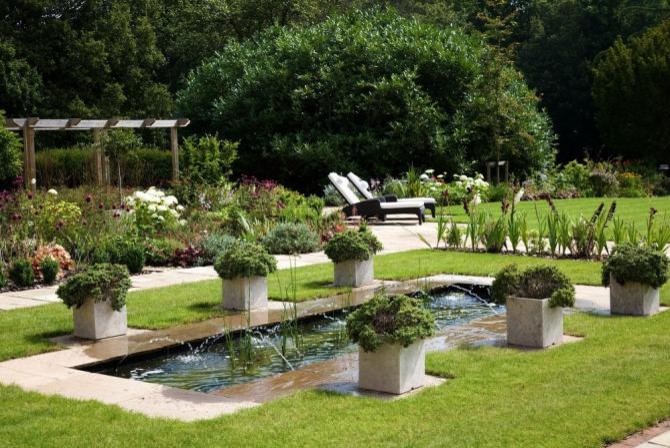 Inspiration for a large contemporary backyard full sun garden in London with a water feature and natural stone pavers.