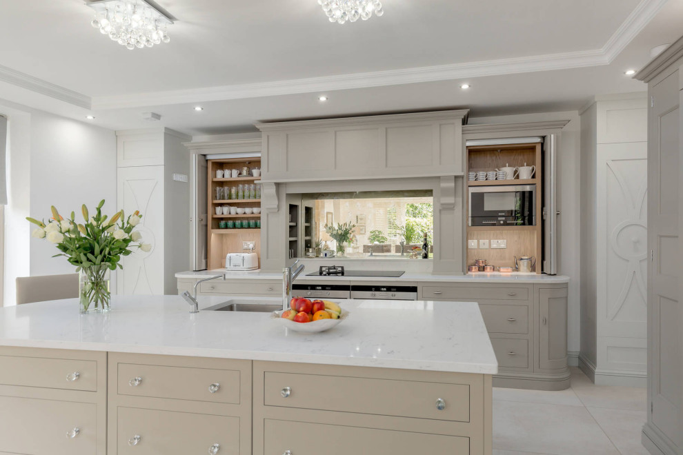 This is an example of a classic l-shaped kitchen in Edinburgh with an integrated sink, shaker cabinets, grey cabinets, quartz worktops, multi-coloured splashback, stainless steel appliances, porcelain flooring, an island, grey floors, white worktops and mirror splashback.