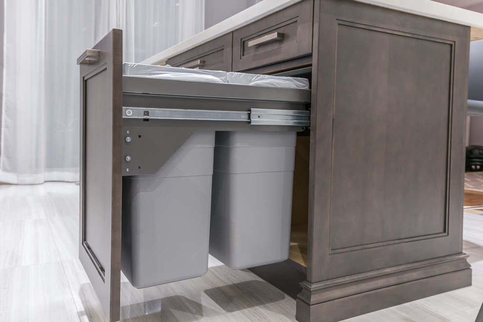 Example of a mid-sized transitional l-shaped porcelain tile eat-in kitchen design in Toronto with a drop-in sink, recessed-panel cabinets, white cabinets, quartz countertops, stainless steel appliances and an island