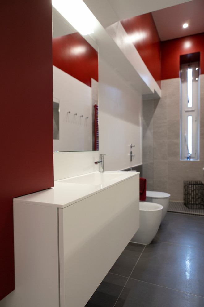 Aménagement d'une salle de bain longue et étroite moderne de taille moyenne avec un placard à porte plane, des portes de placard rouges, WC séparés, un carrelage rouge, un carrelage de pierre, un mur rouge, un sol en carrelage de porcelaine, un lavabo posé, un plan de toilette en quartz modifié, un sol gris, aucune cabine, un plan de toilette blanc, meuble simple vasque et meuble-lavabo suspendu.