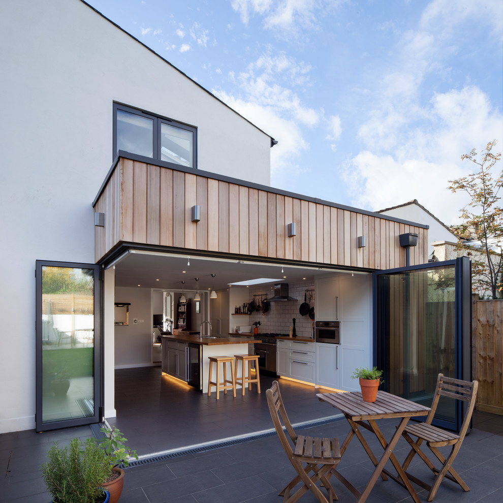 This is an example of a medium sized and white traditional two floor rear extension in London with mixed cladding.
