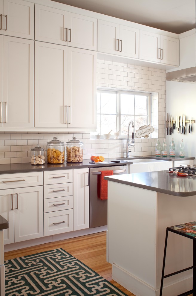 Inspiration for a transitional kitchen in Denver with a farmhouse sink, shaker cabinets, white cabinets, white splashback, subway tile splashback and stainless steel appliances.