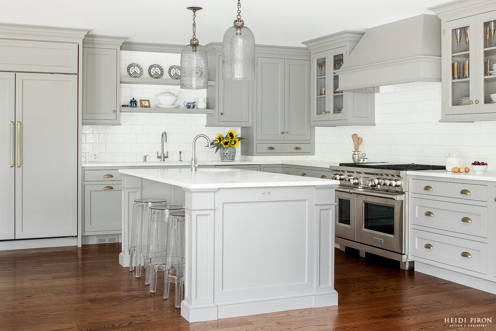 Example of a transitional l-shaped medium tone wood floor eat-in kitchen design in New York with an undermount sink, gray cabinets, marble countertops, white backsplash, stainless steel appliances and an island