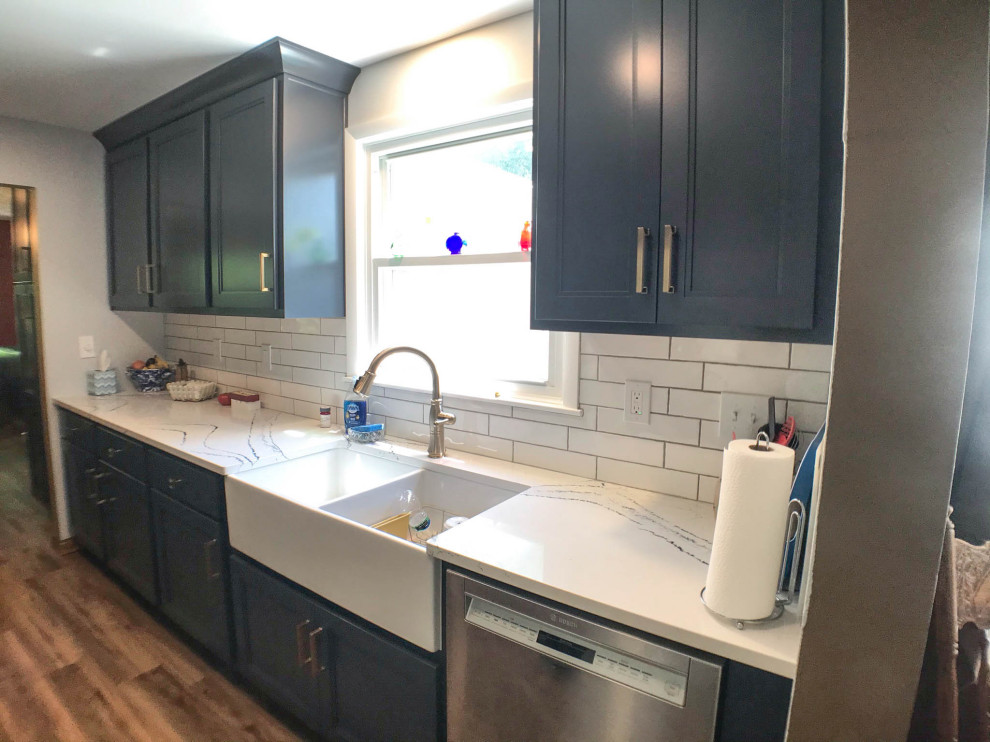 Kitchen - mid-sized transitional galley medium tone wood floor and brown floor kitchen idea with a farmhouse sink, blue cabinets, quartz countertops, white backsplash, glass tile backsplash, stainless steel appliances, no island and white countertops