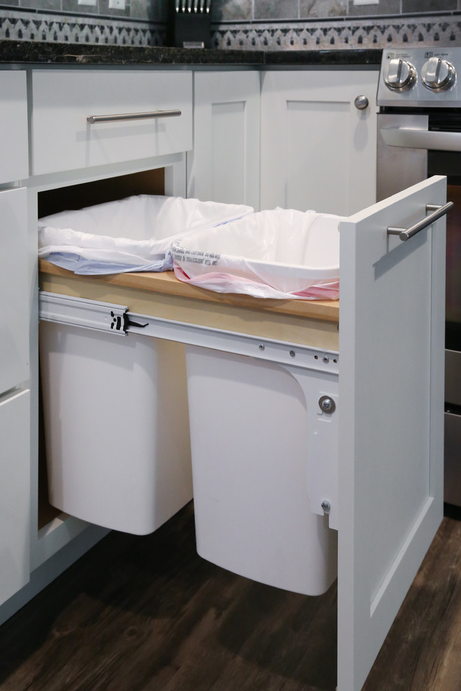 Enclosed kitchen - mid-sized transitional l-shaped medium tone wood floor enclosed kitchen idea in Minneapolis with a double-bowl sink, shaker cabinets, white cabinets, granite countertops, gray backsplash, ceramic backsplash, stainless steel appliances and an island