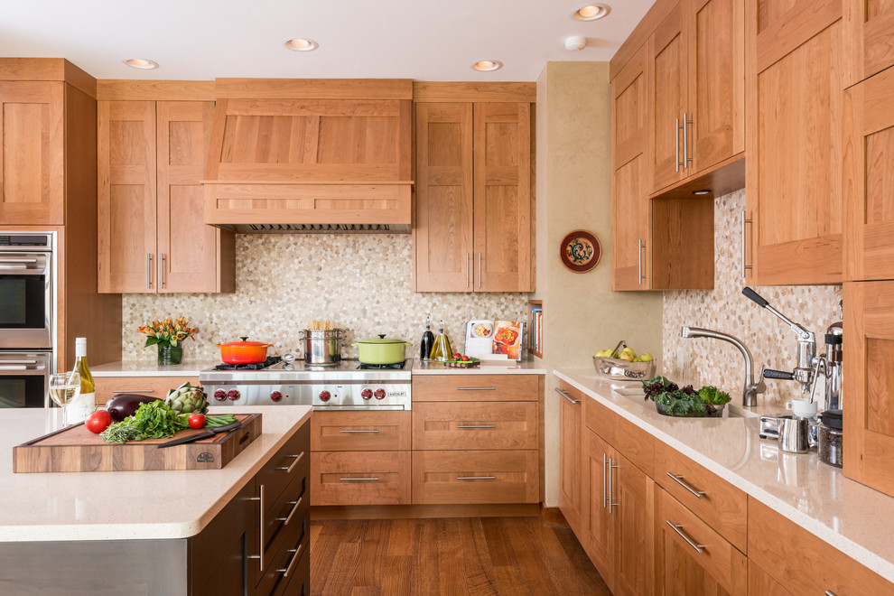 Photo of a mid-sized transitional l-shaped kitchen in Other with an undermount sink, shaker cabinets, medium wood cabinets, quartz benchtops, beige splashback, mosaic tile splashback, medium hardwood floors, with island and stainless steel appliances.