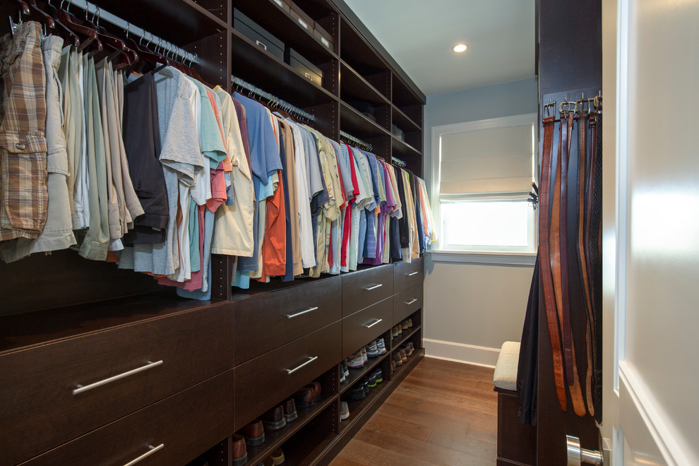 Inspiration for a mid-sized beach style men's walk-in wardrobe in Miami with flat-panel cabinets, dark wood cabinets and dark hardwood floors.