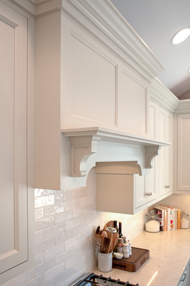 Inspiration for a transitional eat-in kitchen remodel with an undermount sink, shaker cabinets, quartz countertops, white backsplash, ceramic backsplash, stainless steel appliances, an island, white countertops and white cabinets