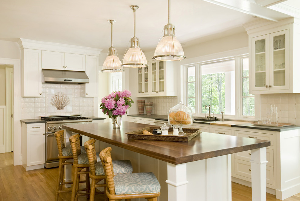 Photo of a large traditional galley eat-in kitchen in Boston with glass-front cabinets, stainless steel appliances, white cabinets, an undermount sink, white splashback, ceramic splashback, medium hardwood floors, with island and wood benchtops.