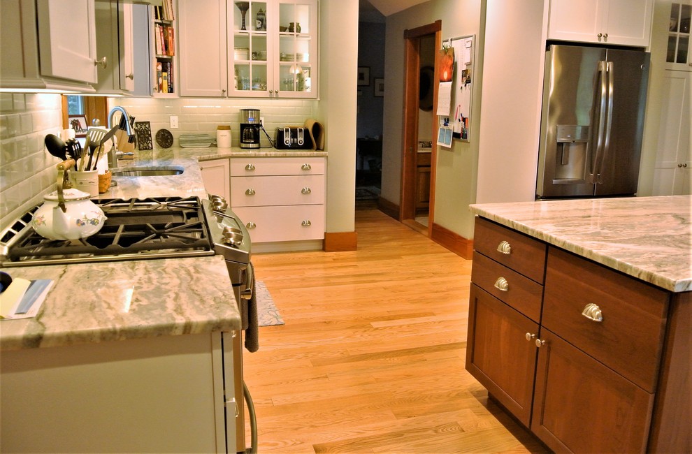 Inspiration for a transitional light wood floor kitchen remodel in Boston with an undermount sink, shaker cabinets, white cabinets, quartzite countertops, white backsplash, subway tile backsplash, stainless steel appliances and an island