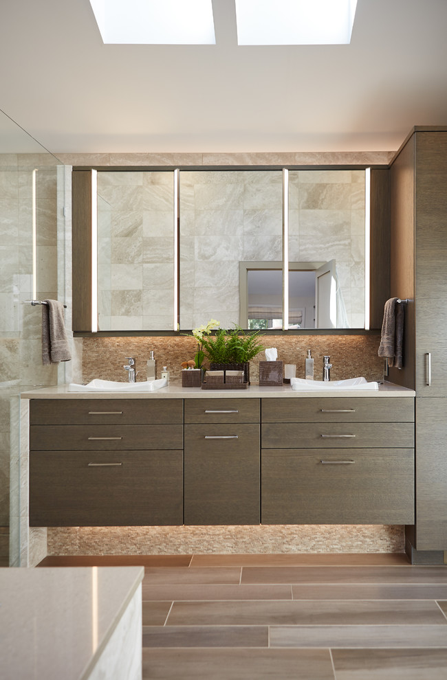 This is an example of a mid-sized contemporary master bathroom in Detroit with flat-panel cabinets, brown cabinets, beige tile, white tile, vinyl floors, a vessel sink, solid surface benchtops and brown floor.