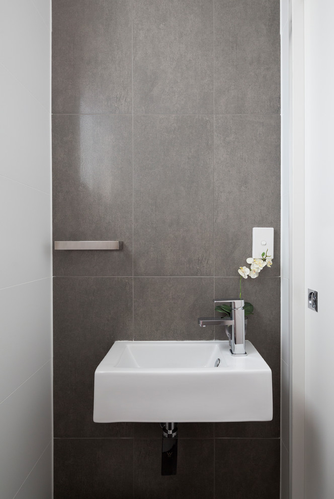 Small contemporary powder room in Brisbane with gray tile, grey walls, a wall-mount sink, ceramic tile and ceramic floors.