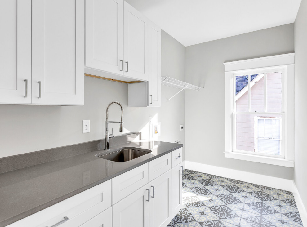 This is an example of a mid-sized transitional single-wall dedicated laundry room in Atlanta with an undermount sink, shaker cabinets, white cabinets, quartzite benchtops, grey walls, ceramic floors, a side-by-side washer and dryer, blue floor and grey benchtop.