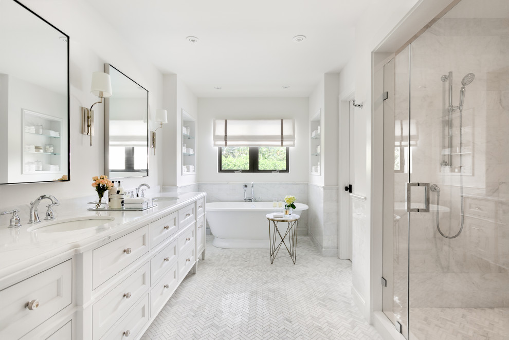 Inredning av ett klassiskt vit vitt badrum, med luckor med infälld panel, vita skåp, ett fristående badkar, en dusch i en alkov, vit kakel, vita väggar, mosaikgolv, ett undermonterad handfat, vitt golv och dusch med gångjärnsdörr