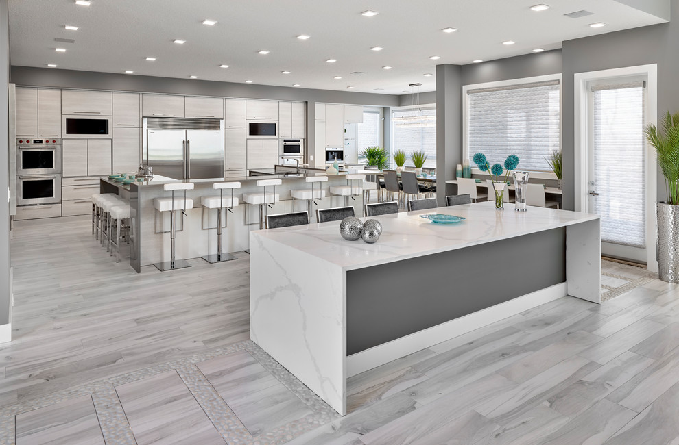 Design ideas for a large contemporary u-shaped eat-in kitchen in Edmonton with an undermount sink, louvered cabinets, grey cabinets, quartz benchtops, stainless steel appliances, porcelain floors, multiple islands, grey floor and white benchtop.
