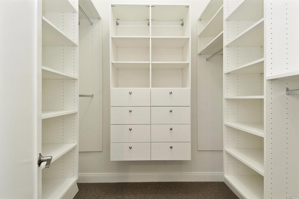 Large beach style gender-neutral walk-in wardrobe in San Francisco with flat-panel cabinets, white cabinets and carpet.