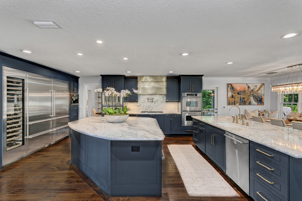 Inspiration for a transitional u-shaped medium tone wood floor and brown floor eat-in kitchen remodel in Orlando with an undermount sink, raised-panel cabinets, blue cabinets, marble countertops, multicolored backsplash, marble backsplash, stainless steel appliances, an island and multicolored countertops