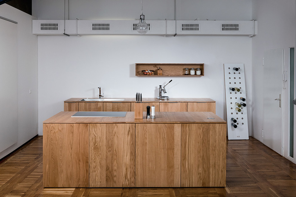 This is an example of a small industrial galley separate kitchen in Other with flat-panel cabinets, medium wood cabinets, wood benchtops, with island, a drop-in sink, panelled appliances and medium hardwood floors.