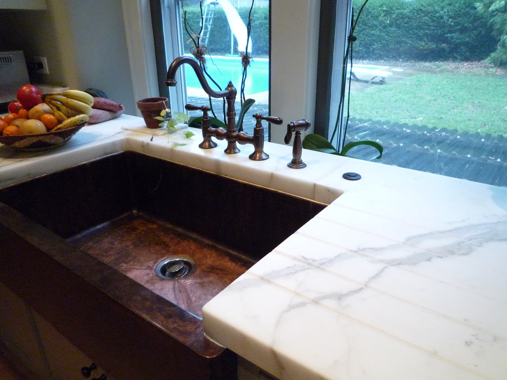 Enclosed kitchen - transitional medium tone wood floor enclosed kitchen idea with a farmhouse sink, flat-panel cabinets, green cabinets, marble countertops, paneled appliances and an island