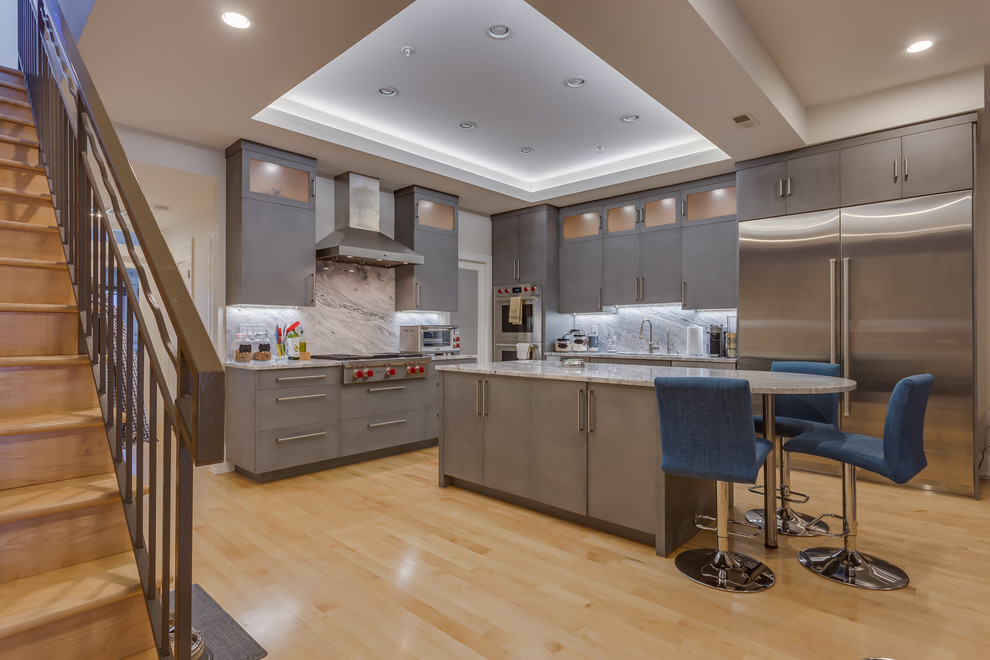 Mid-sized modern l-shaped eat-in kitchen in DC Metro with an undermount sink, flat-panel cabinets, grey cabinets, granite benchtops, white splashback, stone slab splashback, stainless steel appliances, light hardwood floors, with island and beige floor.