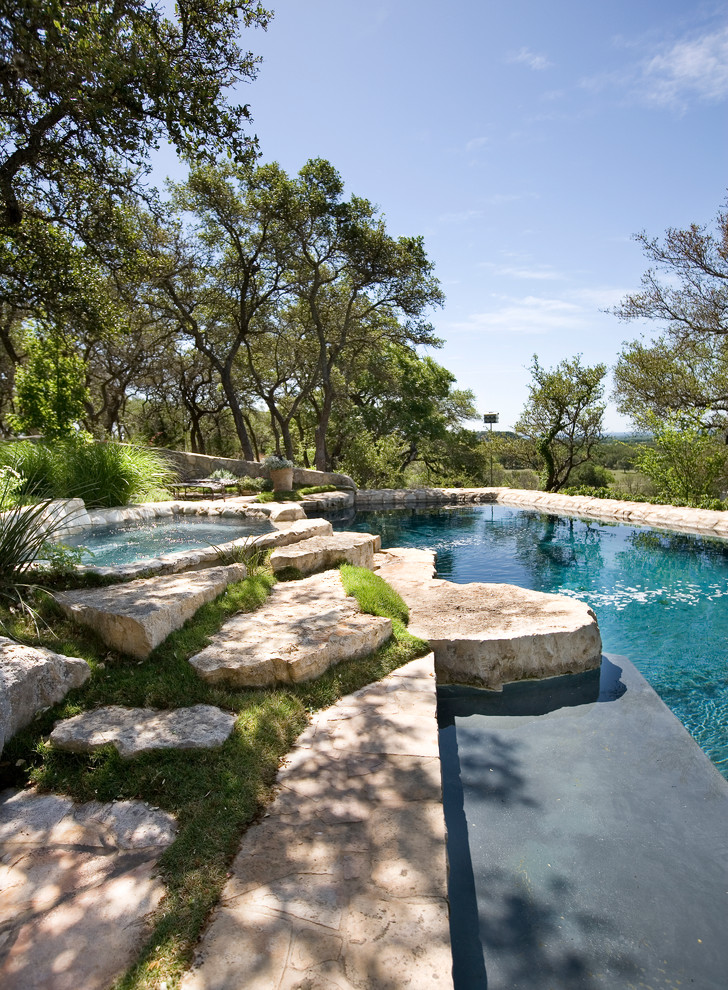 This is an example of a traditional backyard custom-shaped pool in Austin with natural stone pavers.