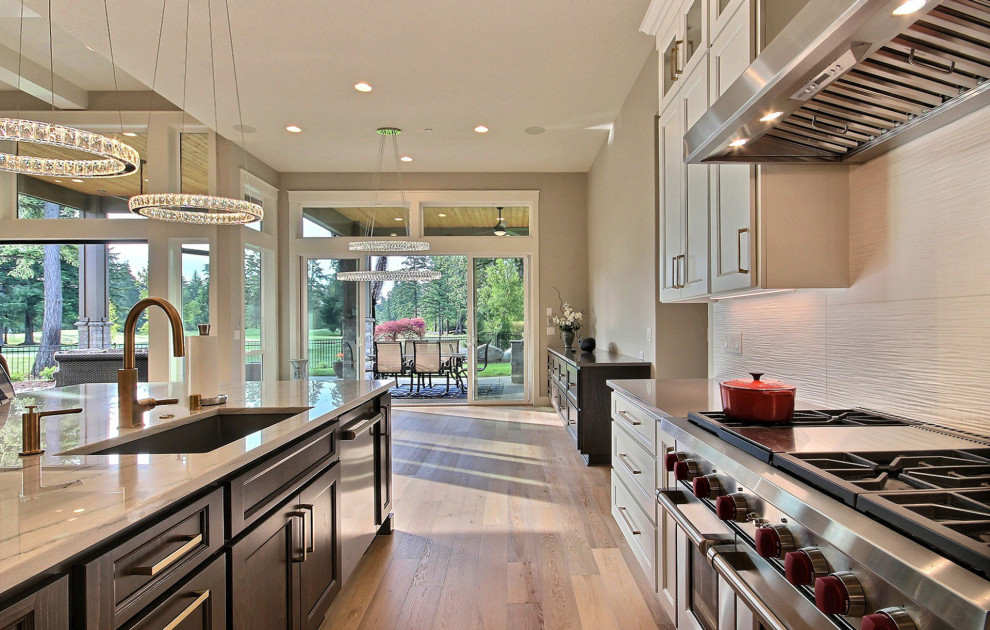 Exempel på ett stort modernt grå grått kök, med en undermonterad diskho, luckor med infälld panel, vita skåp, bänkskiva i kvarts, vitt stänkskydd, stänkskydd i keramik, rostfria vitvaror, ljust trägolv, en köksö och brunt golv
