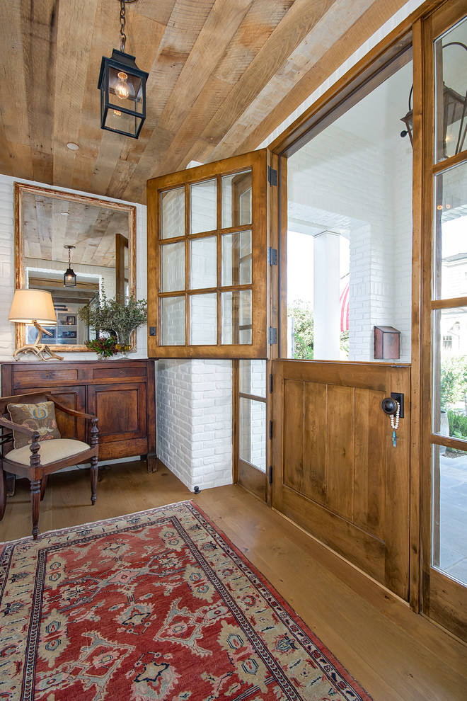 This is an example of a mid-sized country foyer in Orange County with white walls, light hardwood floors, a dutch front door, a medium wood front door and brown floor.