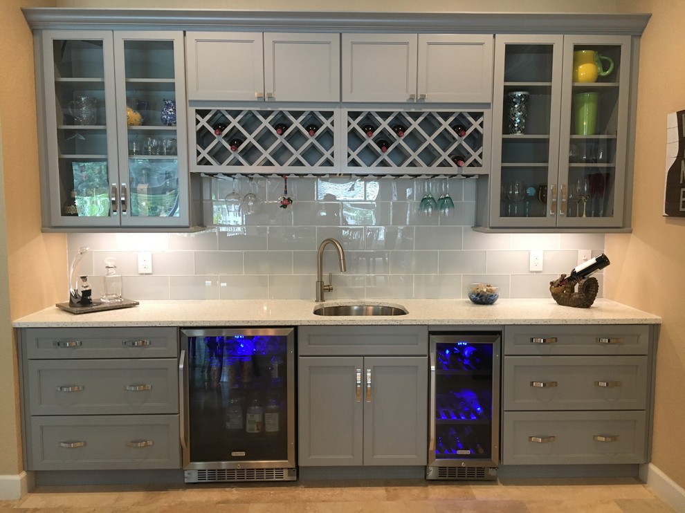 Design ideas for a mid-sized beach style single-wall wet bar in Tampa with an undermount sink, shaker cabinets, grey cabinets, recycled glass benchtops, white splashback, glass tile splashback, travertine floors and beige floor.