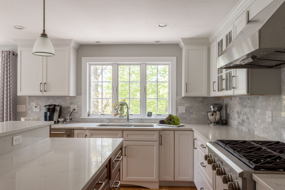 Example of a large transitional l-shaped medium tone wood floor, brown floor and coffered ceiling eat-in kitchen design in Boston with an undermount sink, shaker cabinets, white cabinets, quartz countertops, gray backsplash, subway tile backsplash, stainless steel appliances, an island and white countertops