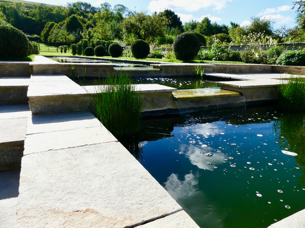 Geometrischer, Großer Moderner Gartenwasserfall hinter dem Haus mit direkter Sonneneinstrahlung und Natursteinplatten in Wiltshire